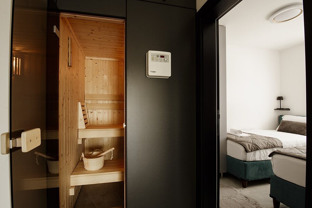 A small wooden sauna with a glass door built next to a bedroom in a modern apartment